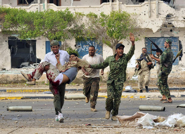 Anti-Gadhafi fighters carry an injured comrade during clashes with Gadhafi forces in Sirte Oct 19, 2011. Gadhafi killed as Libya's revolt claims hometown