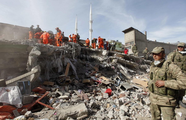 Soldiers stand near rescue workers working to save people trapped under debris after an earthquake in Ercis, near the eastern Turkish city of Van, October 24, 2011. Turkey quake death toll exceeds 260