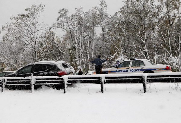 police officer stops next to a car off the road on the Pallisades Interstate Parkway in Bergen County, New Jersey, early on Oct 30, 2011. Rare Oct snowstorm batters Northeast