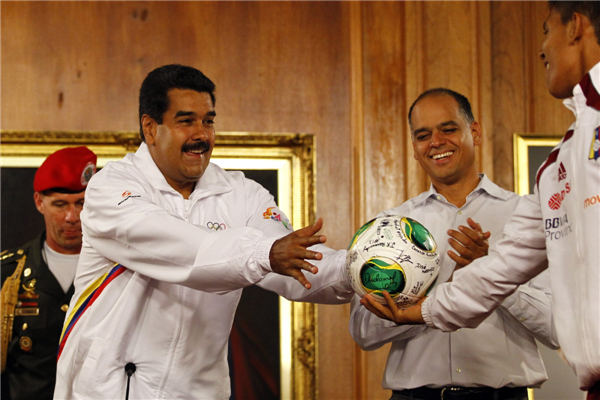 Venezuela's President Nicolas Maduro (L) reaches for a ball from a member of the Venezuela's Under-17 soccer team, during a news conference in Caracas, April 30, 2013. Venezuela's President meets Under-17 soccer team