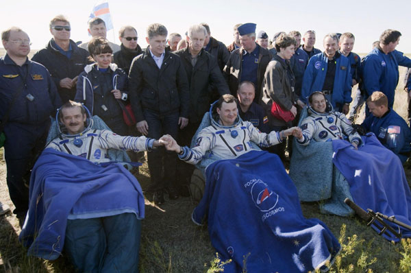 US astronaut Tom Marshburn (right), Russian cosmonaut Roman Romanenko (center) and Canadian astronaut Chris Hadfield pose for a picture after leaving the Russian Soyuz space capsule following its landing, some 150 km (90 miles) southeast of the town of Zhezkazgan in central Kazakhstan May 14, 2013. Russia's Soyuz space capsule returns to Earth