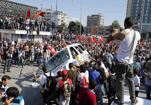 Protesters prepare to roll a police car over during an anti-government protest at Taksim Square in central Istanbul June 1, 2013. Protesters swarm Istanbul square after clashes