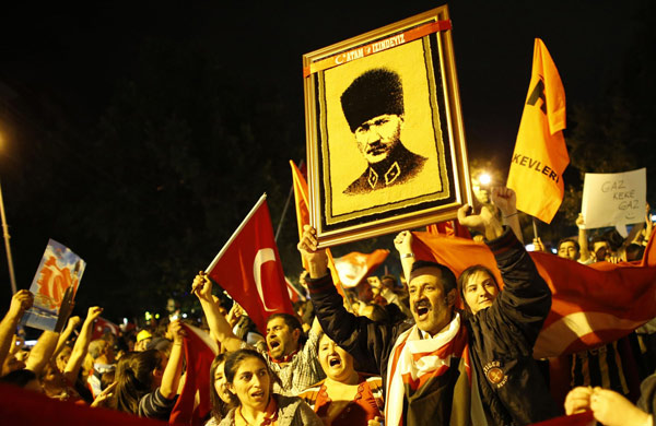Anti-government protesters shout slogans, wave flags and raise a portrait of Mustafa Kemal Ataturk, founder of modern Turkey, during a demonstration in central Ankara June 7, 2013. Clashes continue in Turkey