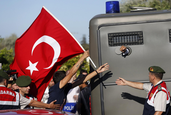 Protesters run after a prison van as an unidentified defendant sticks his fist out as he's driven to a courthouse in Silivri, where a hearing for people charged with attempting to overthrow Prime Minister Tayyip Erdogan's Islamist-rooted government is due to take place, August 5, 2013. A Turkish court on Monday began sentencing nearly 300 defendants accused of plotting to overthrow the government, handing prison sentences of up to 20 years to some and acquitting 21 others. The court was announcing the verdicts individually. Verdicts on high-profile defendants including former armed forces commander Ilker Basbug were yet to be announced. Turkish police clash with protesters over coup trial
