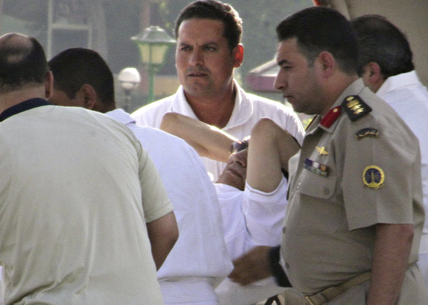 Egyptian army soldiers and medics escort former president Hosni Mubarak after he arrives at a military hospital in the southern suburb of Maadi on the outskirts of Cairo, August 22, 2013. Mubarak leaves prison for house arrest
