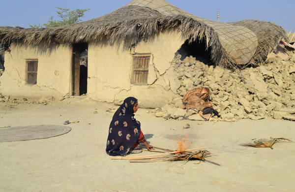 A survivor of an earthquake burns wooden sticks near the rubble of a mud house after it collapsed following the quake at Dhallbedi Peernder village in Awaran district, southwestern Pakistani province of Baluchistan, September 27, 2013. Aftershock kills 15 in quake-hit Pakistan province