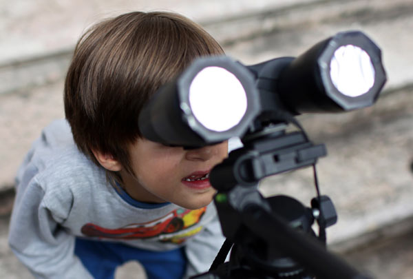 A boy looks through binoculars fitted with homemade filters trying to catch a glimpse of a rare solar eclipse on Sunday outside Lisbon’s Astronomical Observatory. Armando Franca / Associated Press Kenya enhances security as tourists flock to see eclipse